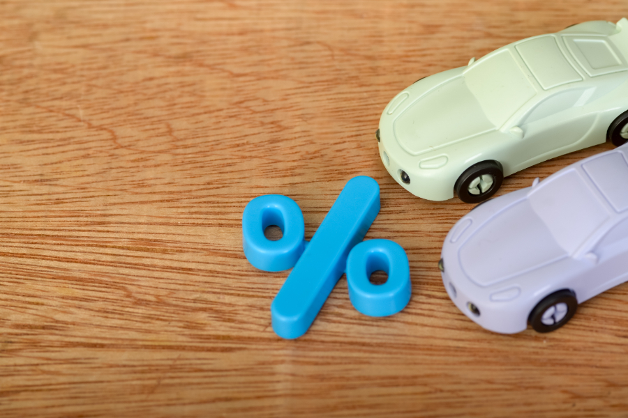 Un symbole de pourcentage bleu et des voitures en miniatures fabriqués en plastique dur