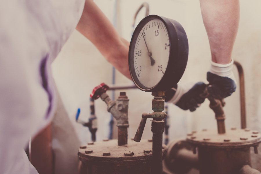 Un homme réparant un compteur d'eau extérieur rempli d'eau 