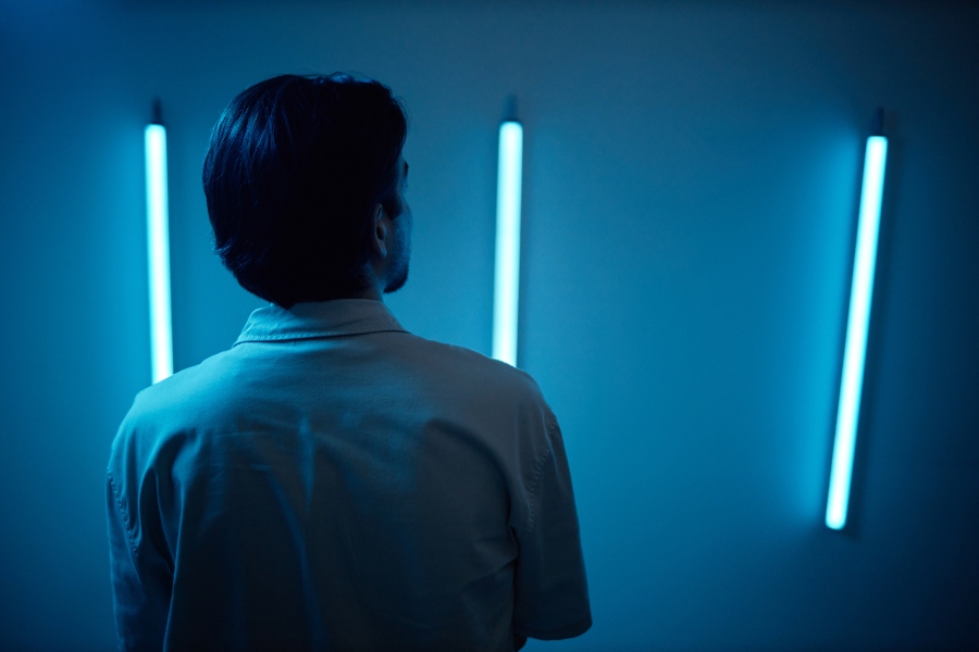 Un plafonnier équipé d’un néon, avec une main qui appuie sur les clips de fixation du cache pour le retirer