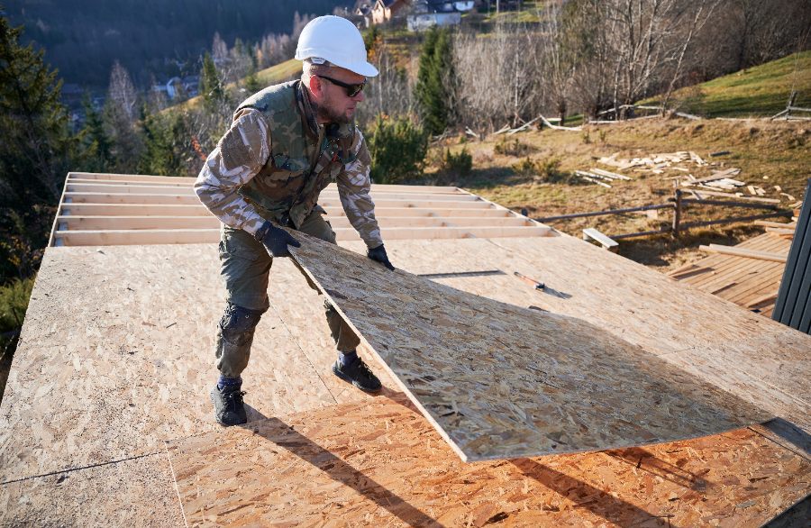 Un chantier en rénovation avec un sol de terre battue partiellement recouvert par un plancher OSB