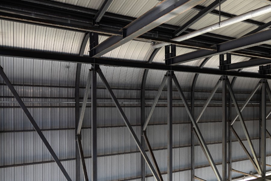 Artisan fixant des plaques de bac acier sur la charpente d’un petit garage
