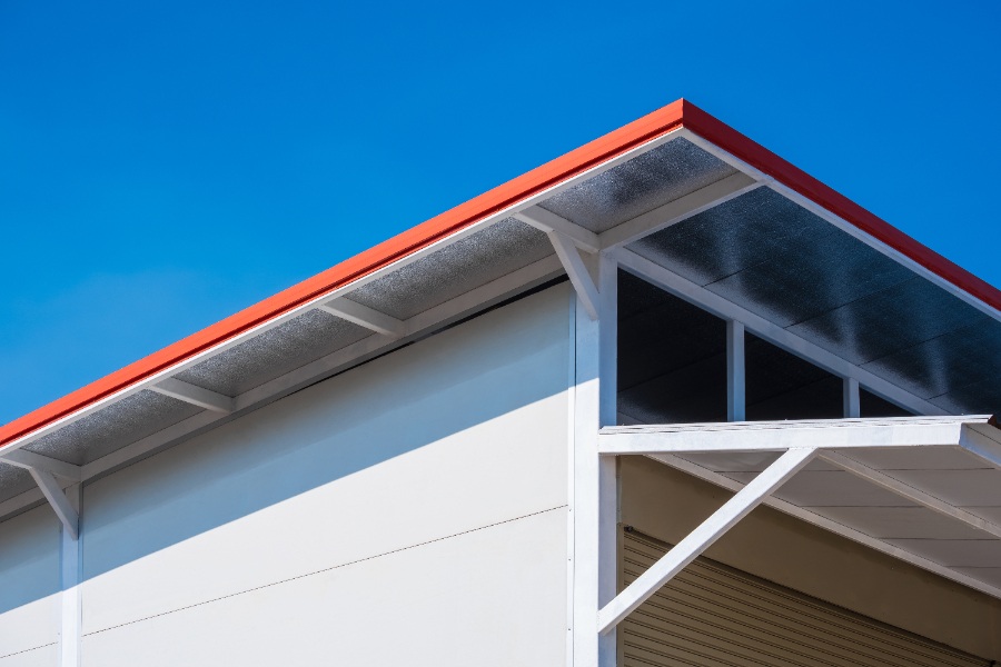 Garage en maçonnerie surmonté d’un toit à une seule pente recouvert de plaques de bac acier gris