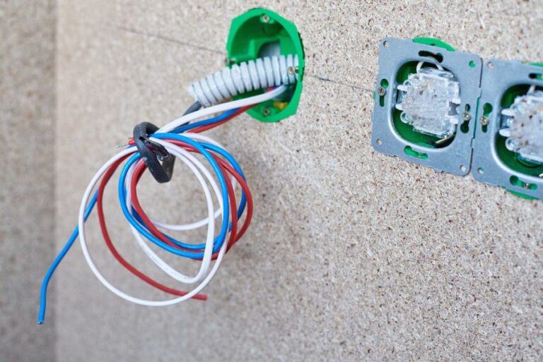 Un technicien connecte les deux fils d’un interphone mural dans un immeuble moderne