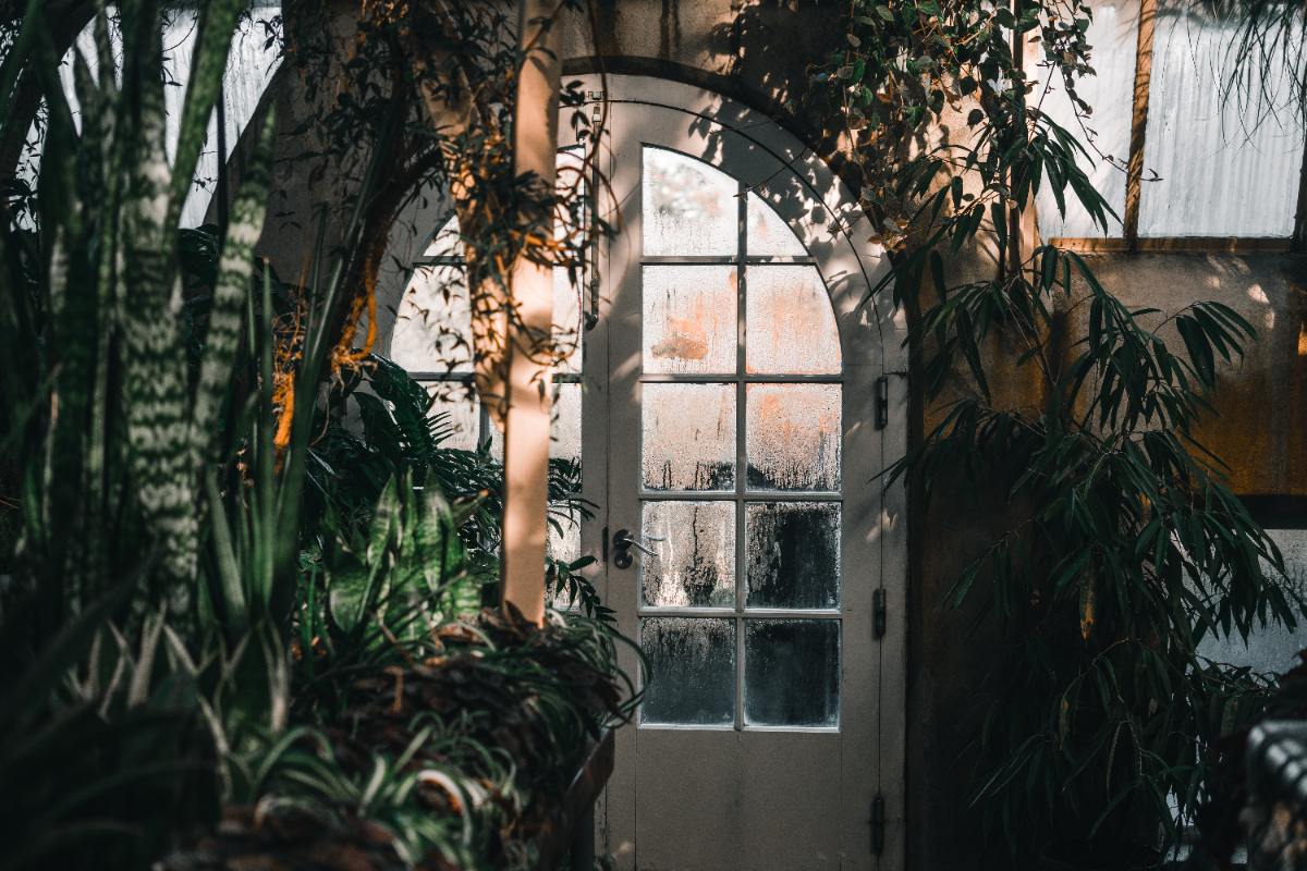 Des tasseaux en bois découpés et alignés au sol, prêts à être assemblés pour former une porte de serre