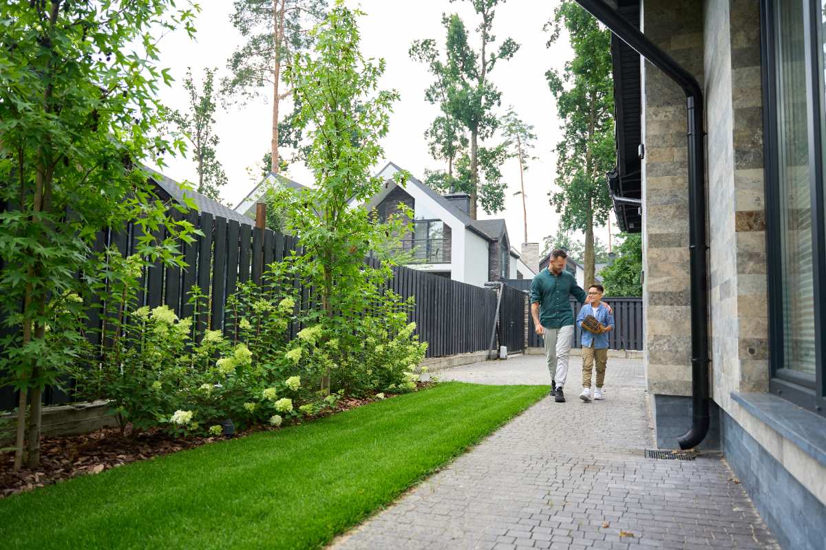 Des personnes marchant sur le trottoir devant une maison