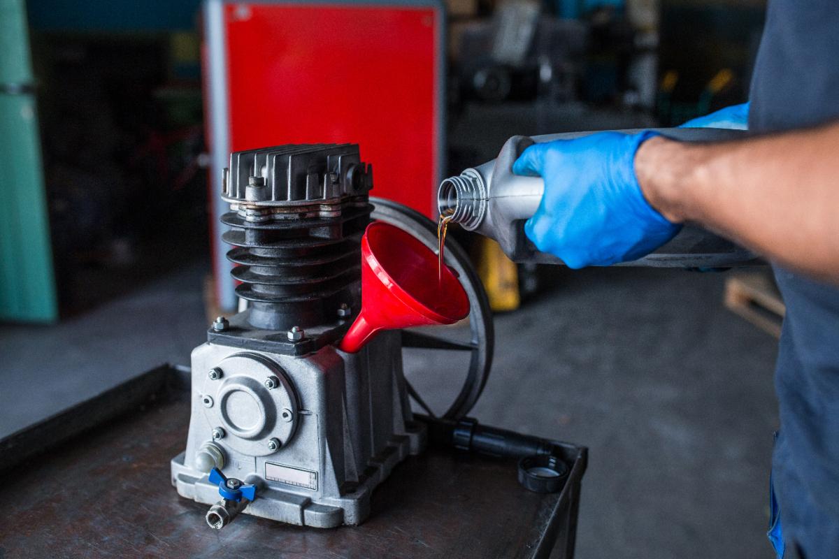 Main ajoute de l'huile dans un compresseur 50 L