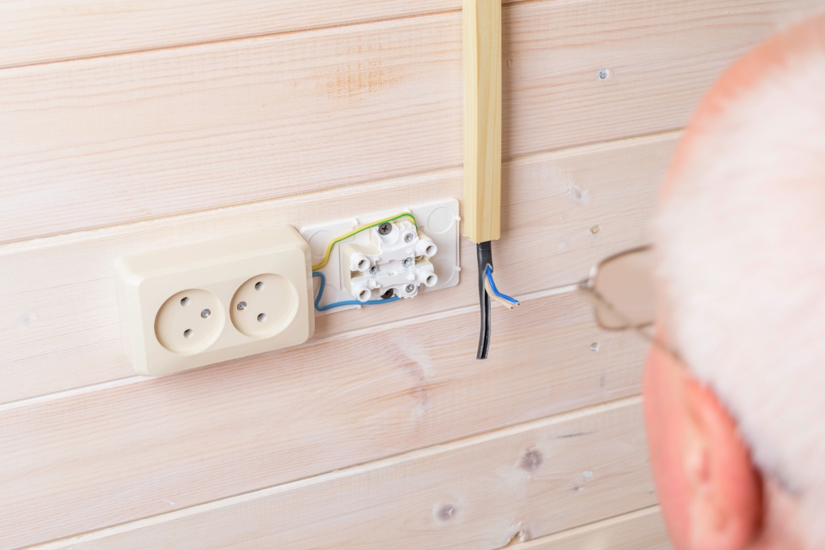 Un électricien qui fait un branchement d'extracteur d'air sur une interrupteur de lumière