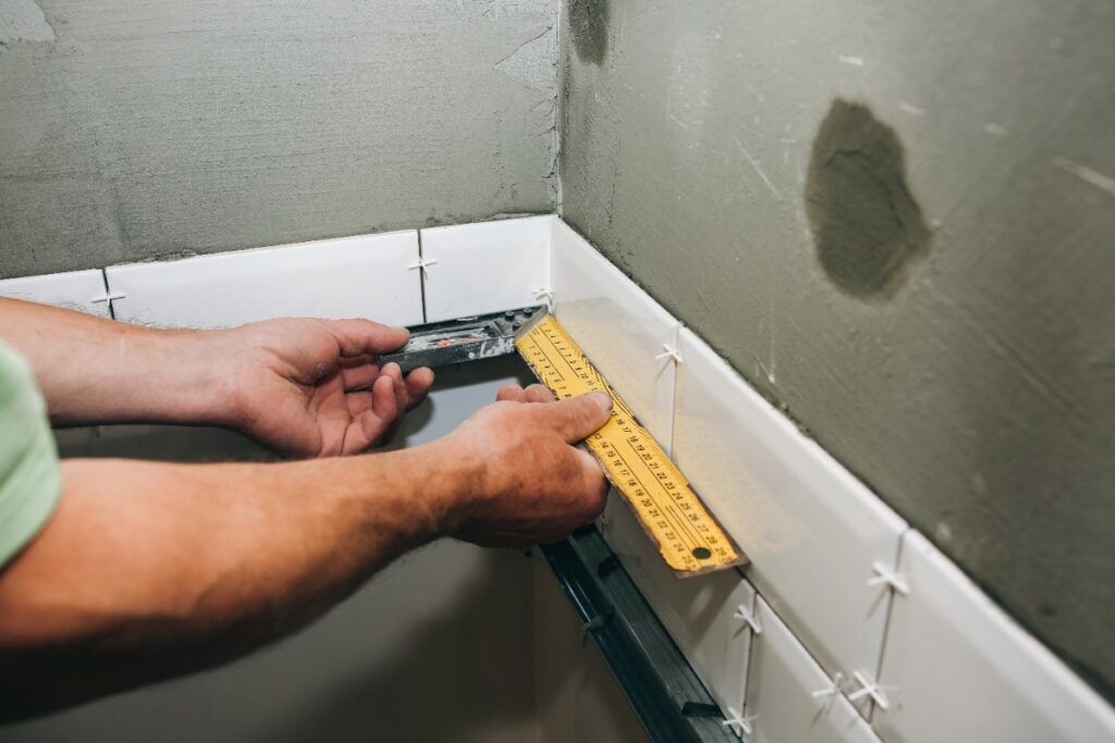 Main d'un homme qui fait une pose carrelage pour la douche