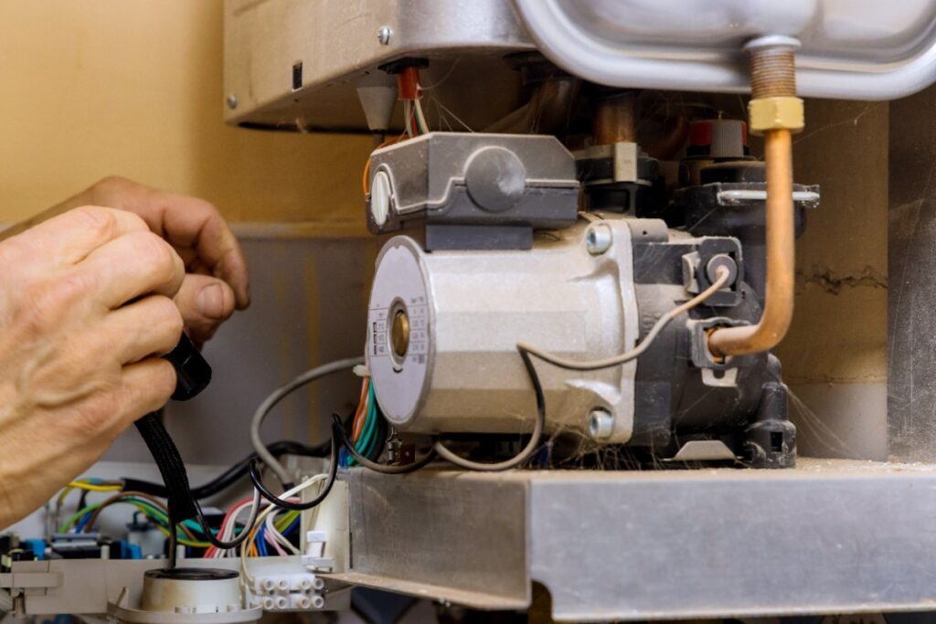 Un technicien qui change le capteur de pression de la chaudière Frisquet Hydromotrix