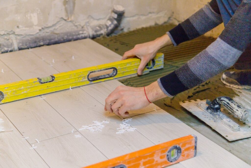 Un ouvrier posant un niveau sur le sol en carrelage