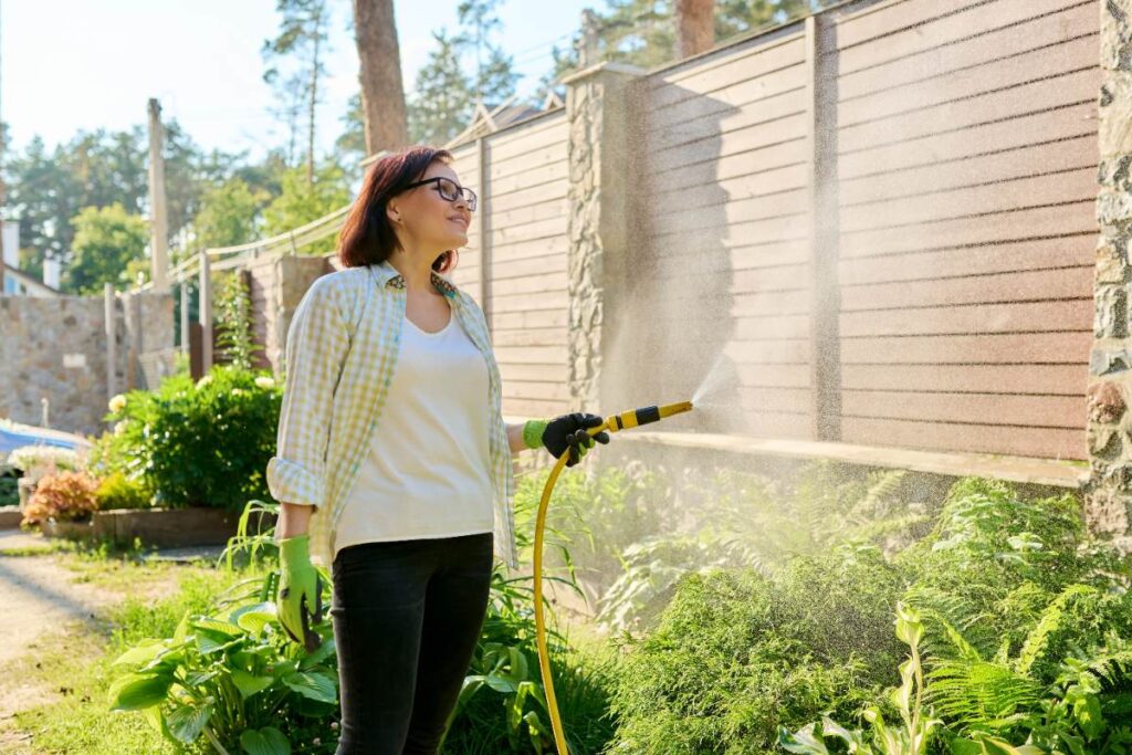 Une femme qui décape un abri de jardin en bois avec un karcher