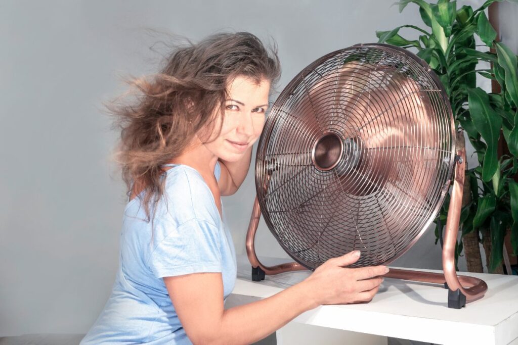 Une femme assise avec un ventilateur sur la table