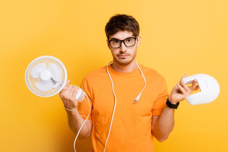Un homme confus avec une lunette, tenant un ventilateur