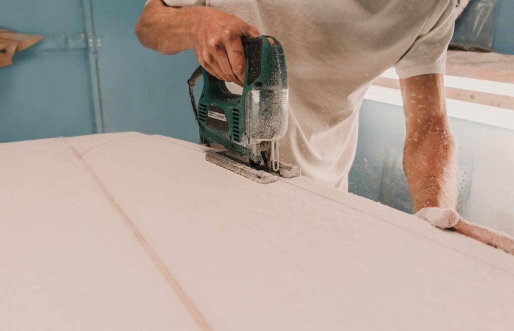 Un homme utilisant un outil en sciant du placo