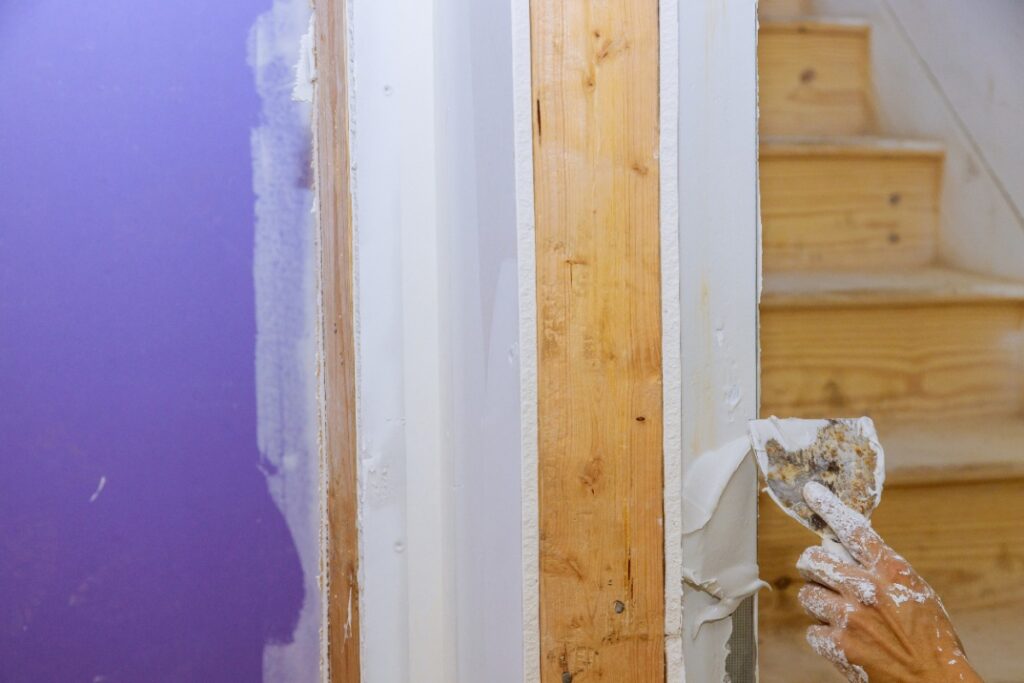 Main d'un travailleur plâtrant un mur en bois
