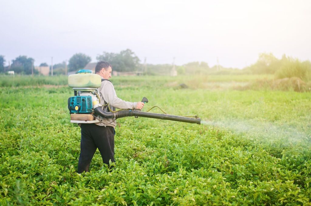 Un agriculteur qui utilise un pulvérisateur sur un champ agricole