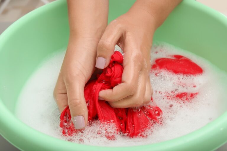 Une femme qui nettoie du linge rouge dans une cuvette