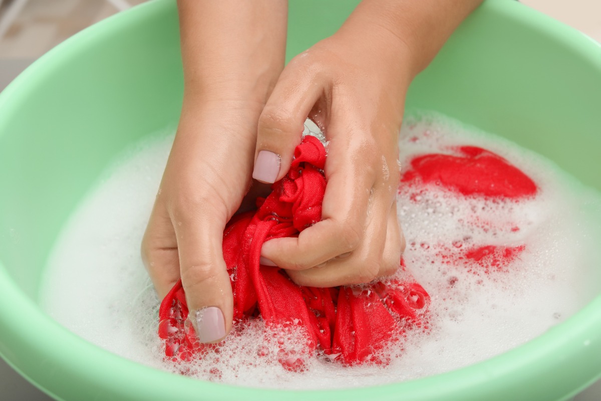 Une femme qui nettoie du linge rouge dans une cuvette
