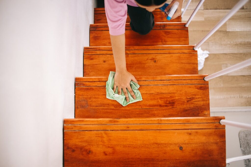 Une personne qui utilise un chiffon pour nettoyer l'escalier en bois