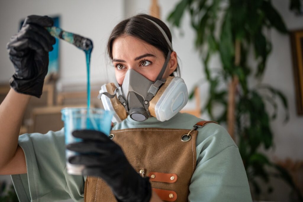 Une femme portant un masque et mélangeant de la peinture bleu