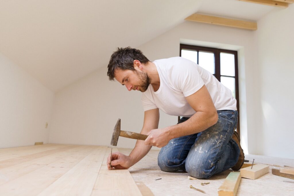 Un homme barbu qui installe du parquet en bois
