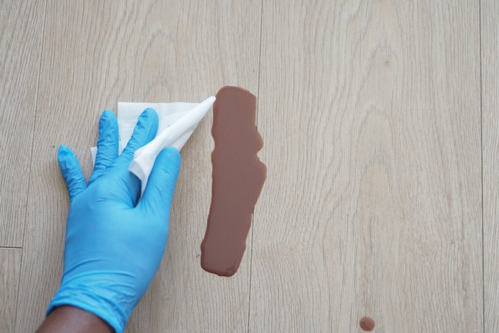 Main d'une personne avec un gant et qui nettoie une tâche de peinture