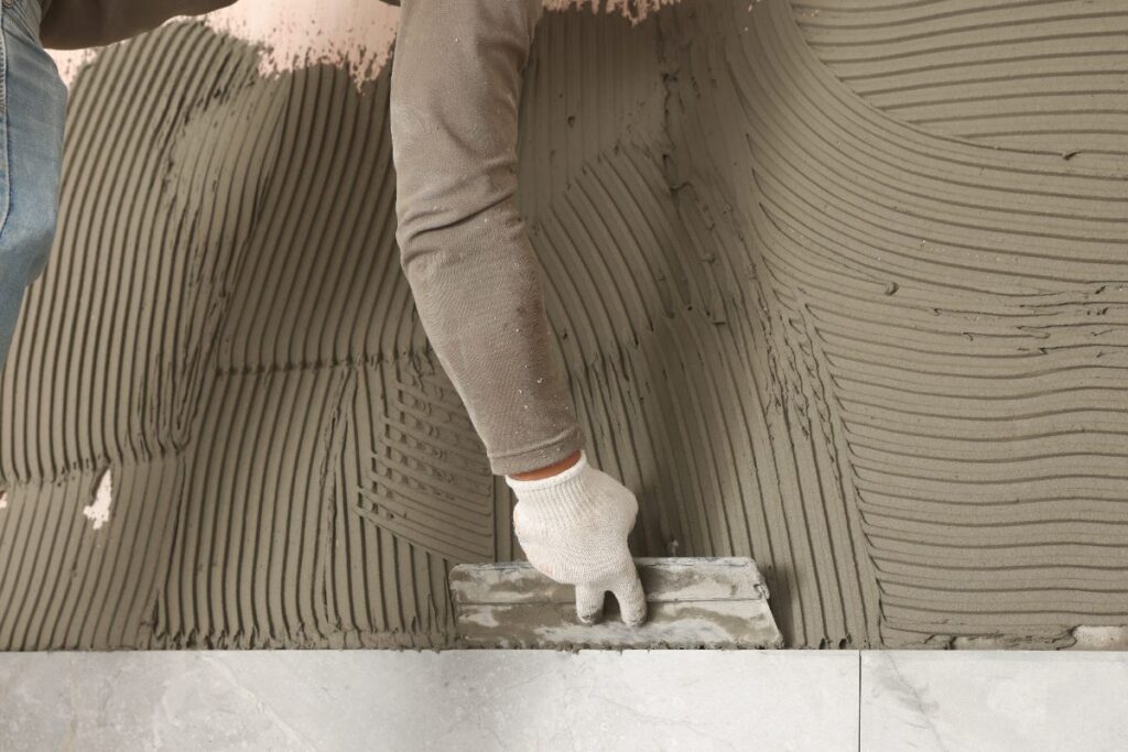 Un ouvrier qui applique du ciment pour une pose de carrelage