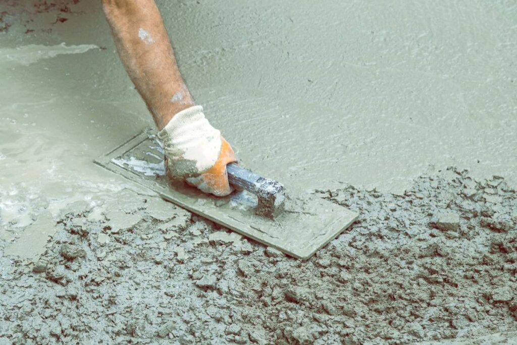 Un ouvrier lissant le ciment sur un chantier