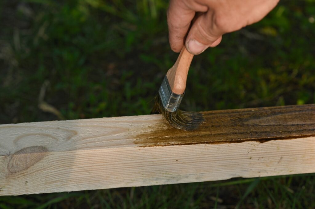 Une personne qui applique de la teinture sur du bois