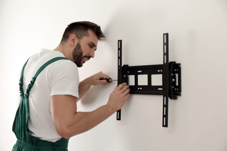 Un homme assemblant un support mural de télévision