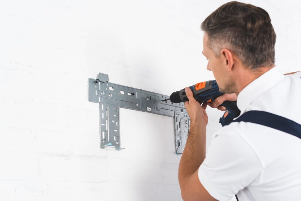 Un homme qui installe un support télévision sur le mur