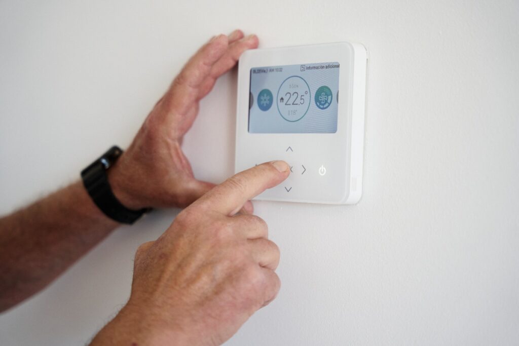 Main ajustant un thermostat sur le mur