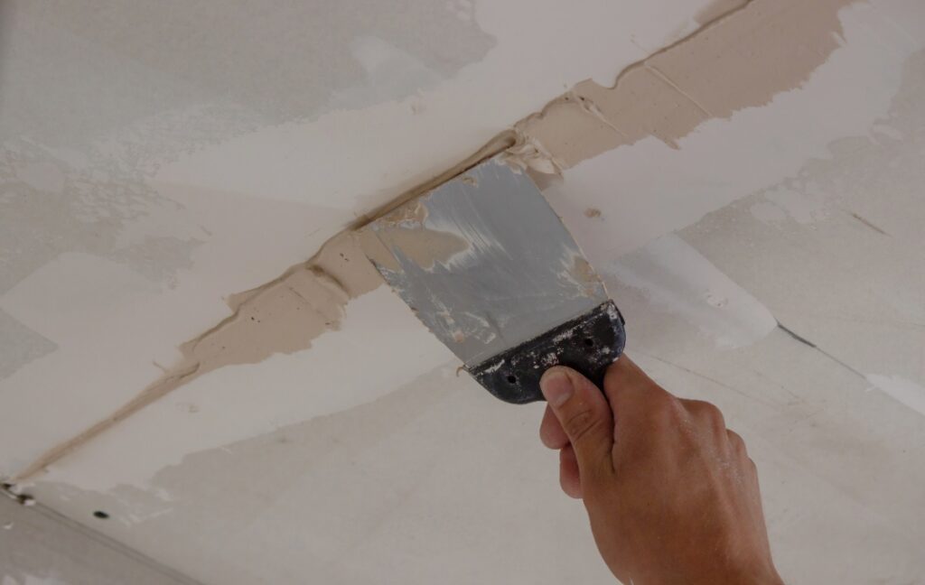 Main plâtrant le plafond