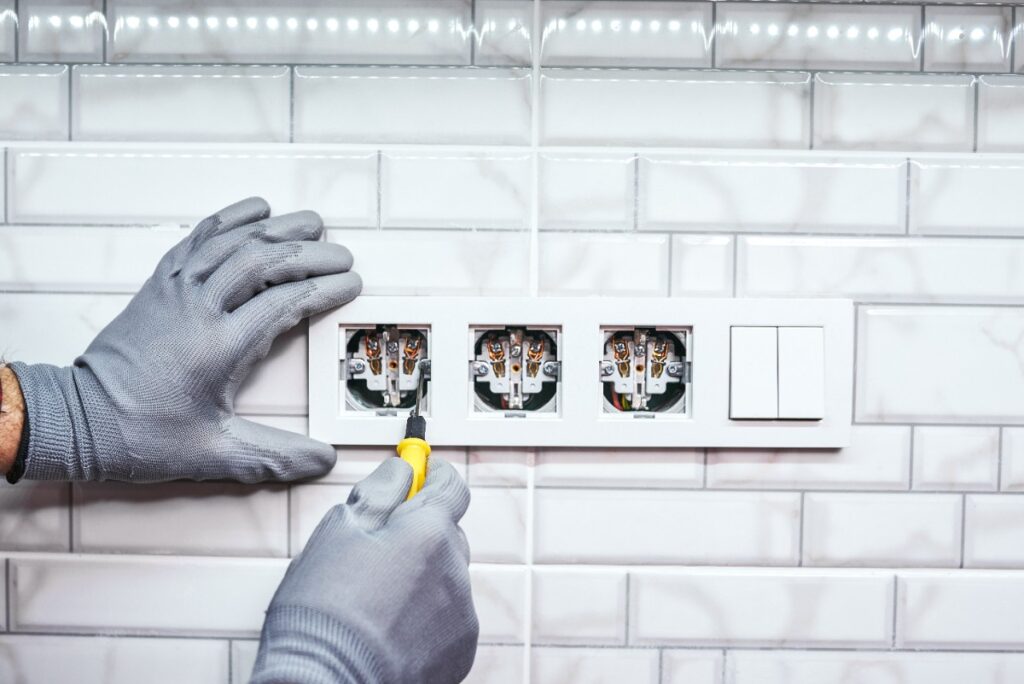 Mains gantées installant une prise électrique