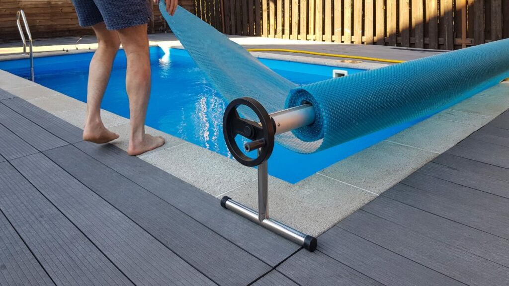 Un homme couvrant la piscine avec une bâche à bulles