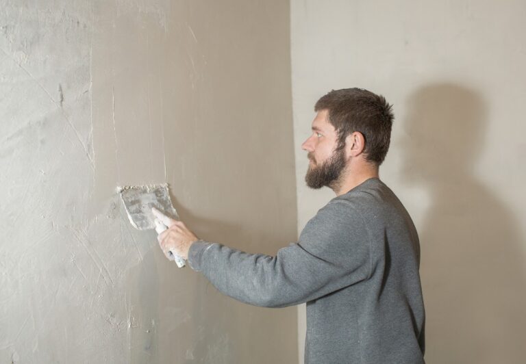 Un homme lissant de l'enduit sur le mur